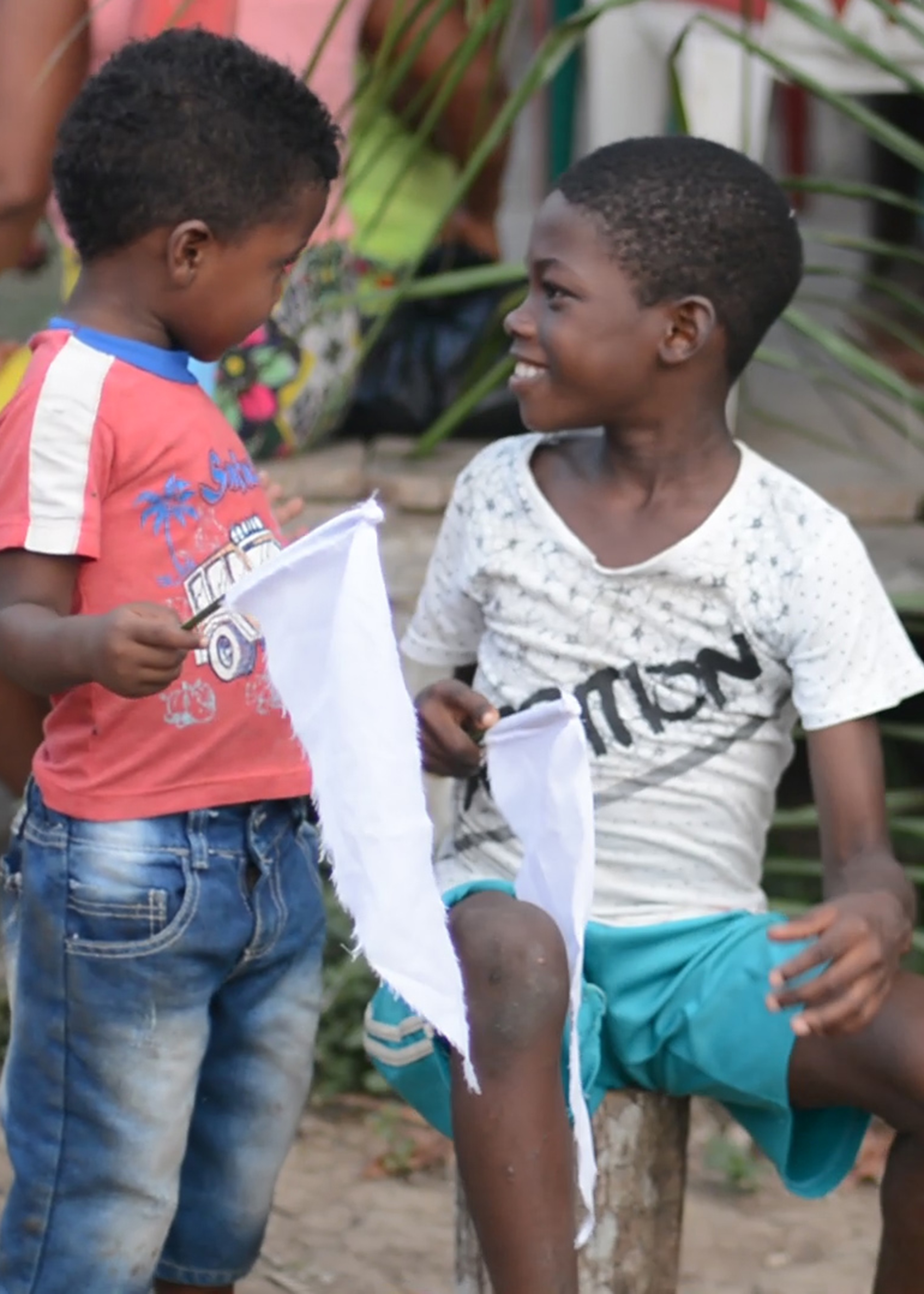 Two boys smile at each other holding white flags