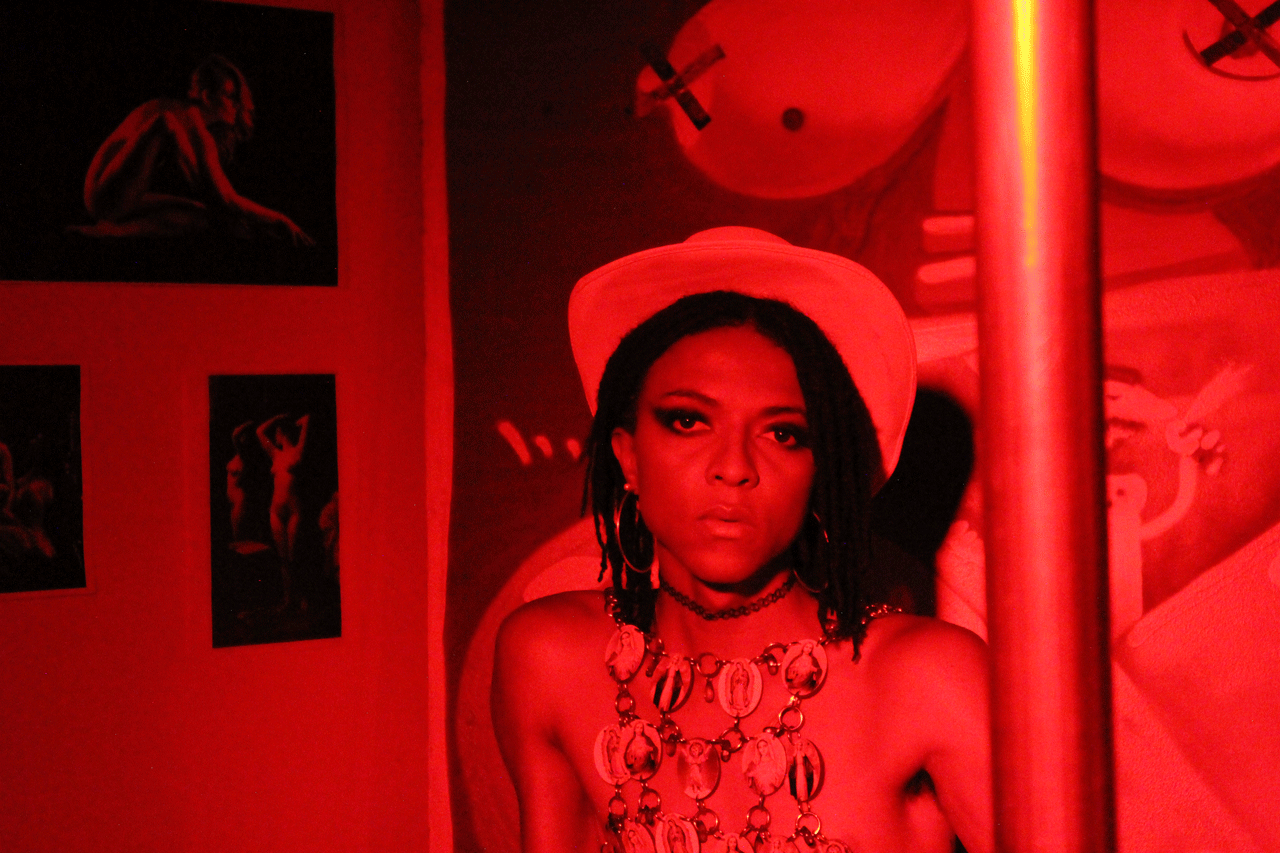 Una mujer negra se sienta a la derecha del marco bajo una luz roja.