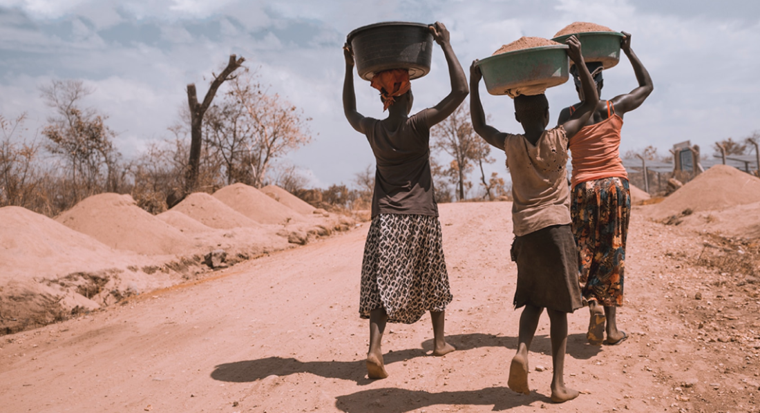 three women walking down a road carrying baskets