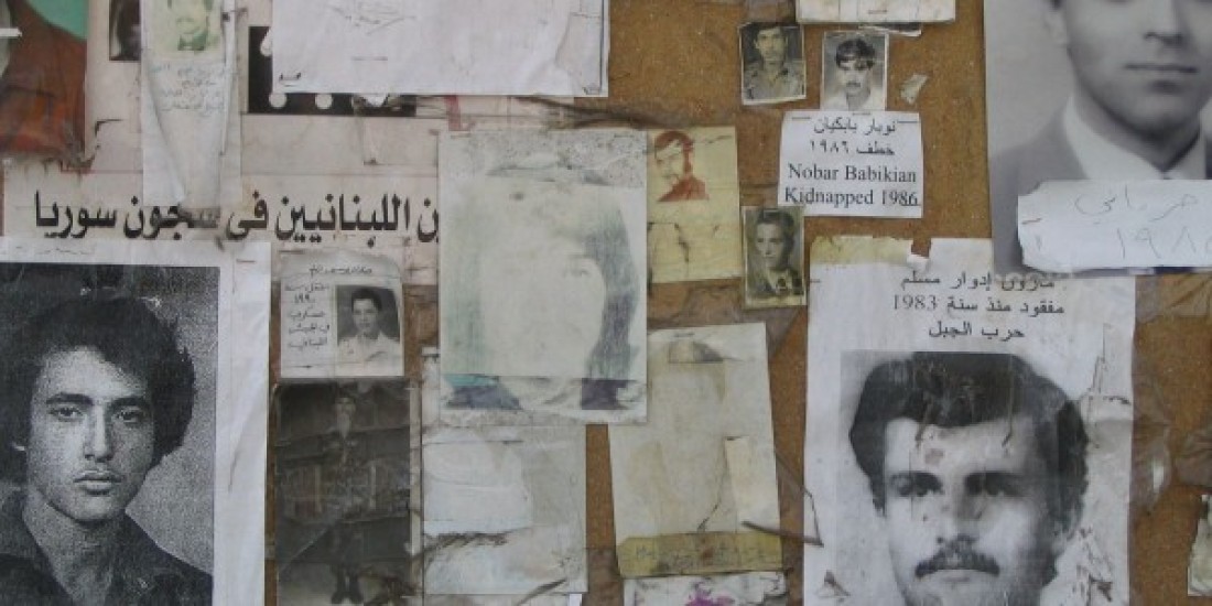 Black and white pictures and old documents of people who have disappeared in Lebanon pasted on a wall.