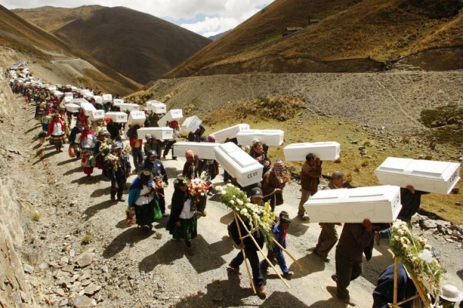 Image des proches des victimes tuées dans un massacre portant des cercueils lors d'une cérémonie de réinhumation