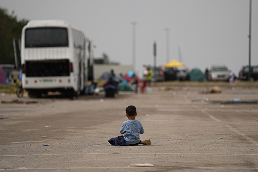 A boy sits on a road, back facing the camera