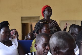 A woman stands up to speak in a room of seated participants at an ICTJ-organized workshop in Uganda.