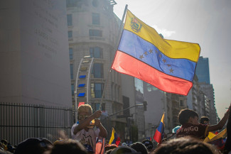 A person waves the Venezuelan flag on city street at night