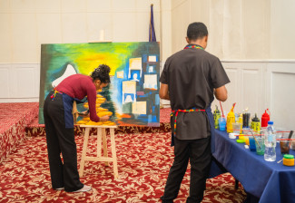 Two people paint on a large canvas