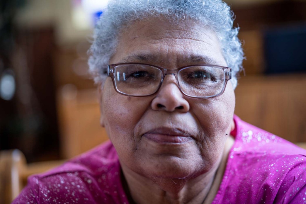 I woman with short hair and glasses looks directly into the camera.