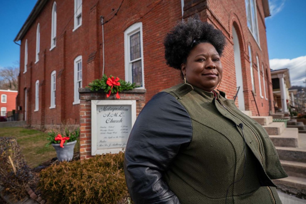 A young woman stands outside a church posing for a photo.
