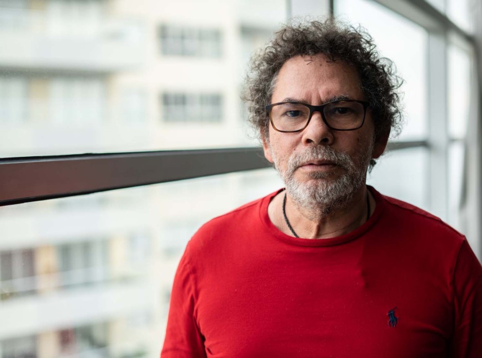 A man in glasses and a red shirt gazes at the camera.
