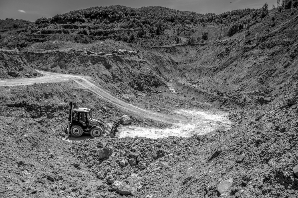 A bulldozer moves earth around a the bottom of a pit.