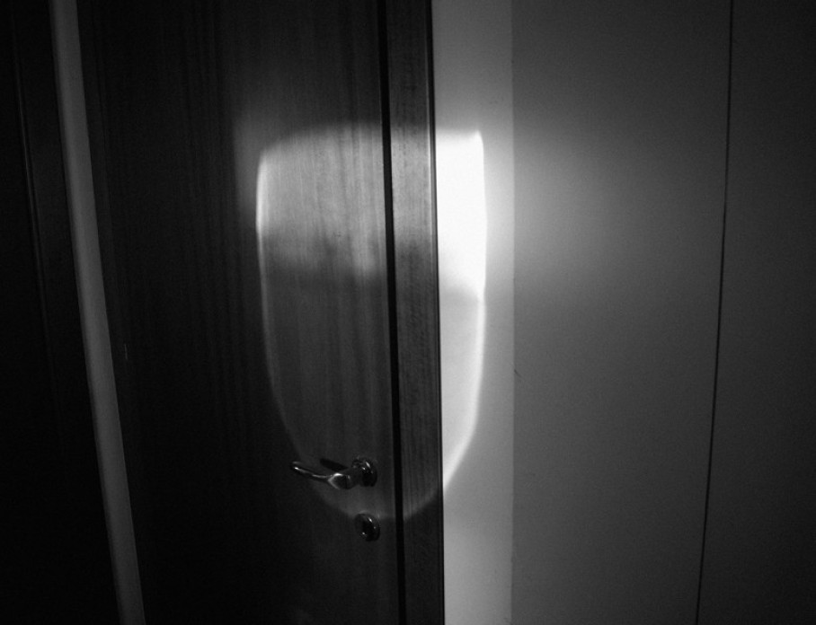 A black and white artistic photograph of a door with intense shadows and highlights