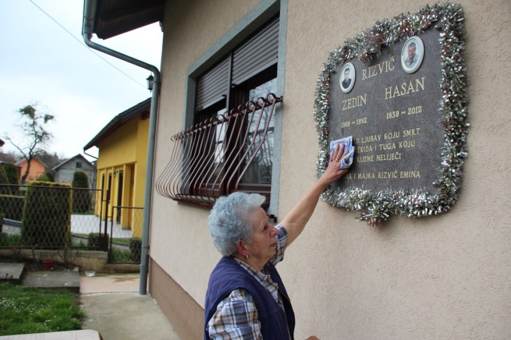A woman beneath a plaque on a house.